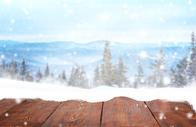 superficie di legno nella neve sullo sfondo di un bosco innevato