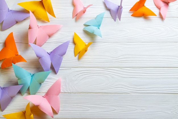 Superficie in legno bianco con un mazzo di farfalle colorate di carta origami con copia spazio per il testo