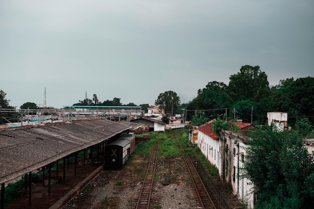 Superficie ruvida della vecchia stazione ferroviaria indiana e vecchi edifici bianchi con superficie nuvolosa scura