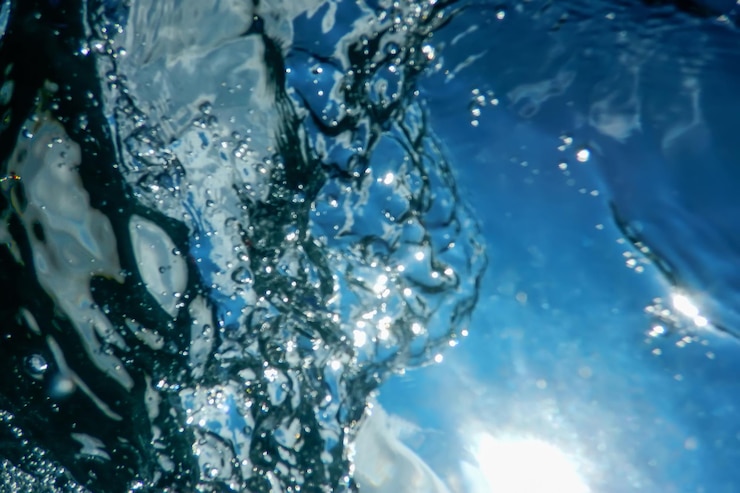Foto superficie subacquea blu e increspature, sfondo di raggi solari subacquei