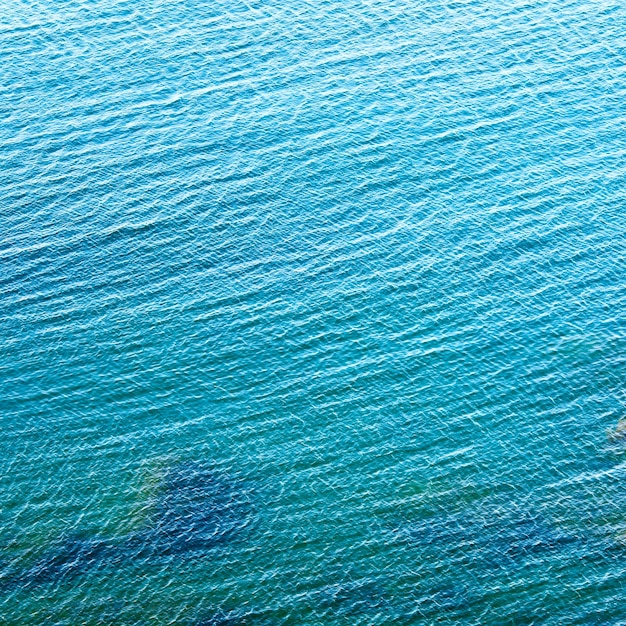 Superficie trasparente dell'acqua azzurra costiera con alcune pietre sul fondo