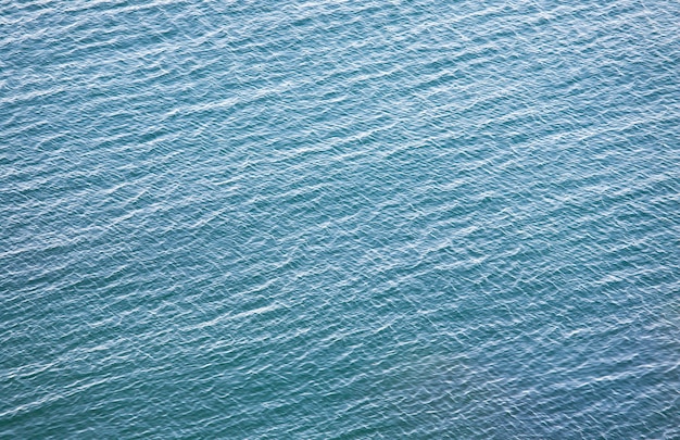 Superficie trasparente dell'acqua azzurra costiera con alcune pietre sul fondo