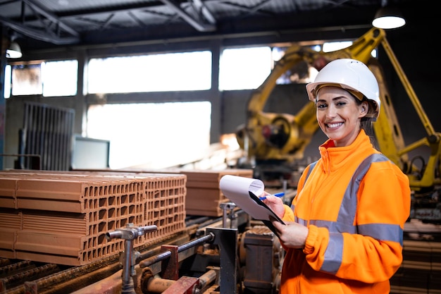 Supervisore femminile che controlla la qualità dei prodotti nella linea di produzione della fabbrica