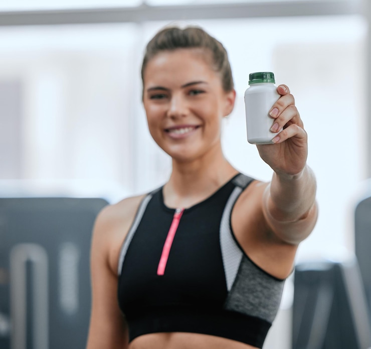 Foto supplementi atleta e donna con sorriso in palestra orgoglioso e felice con l'aiuto di pillole per il fitness health club routine e allenamento con bottiglia di farmaci di miglioramento bodybuilder e abbigliamento sportivo per ragazza