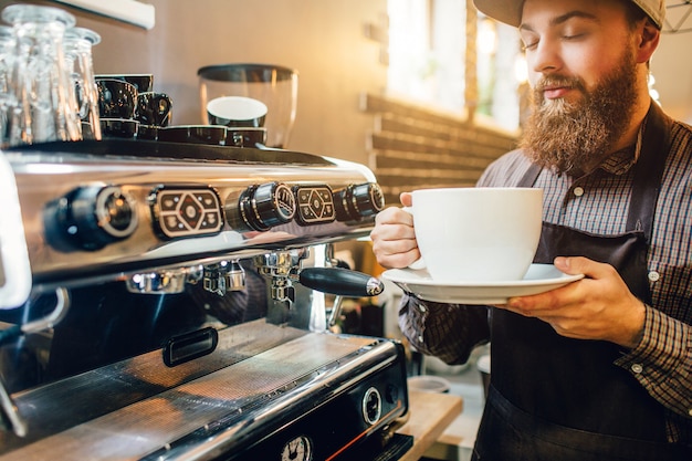 Supporto calmo del giovane alla macchina del caffè in cucina