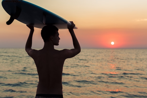 Surfer tenendo la sua tavola da surf e in cerca di onde