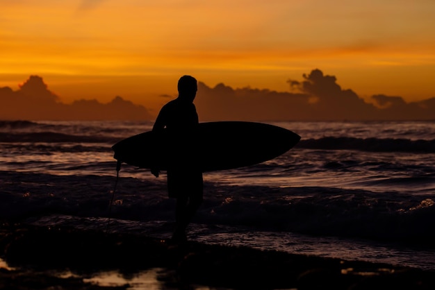 Surfista che entra in acqua al tramonto nebbioso