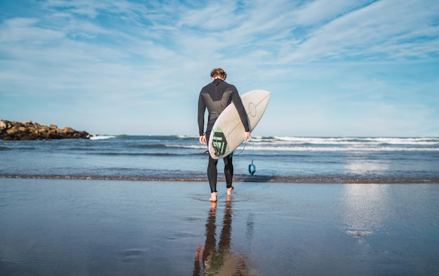 Surfista che entra nell'acqua con la sua tavola da surf.