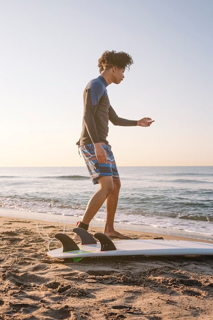 Surfista che si prepara a navigare sulla spiaggia all'alba.