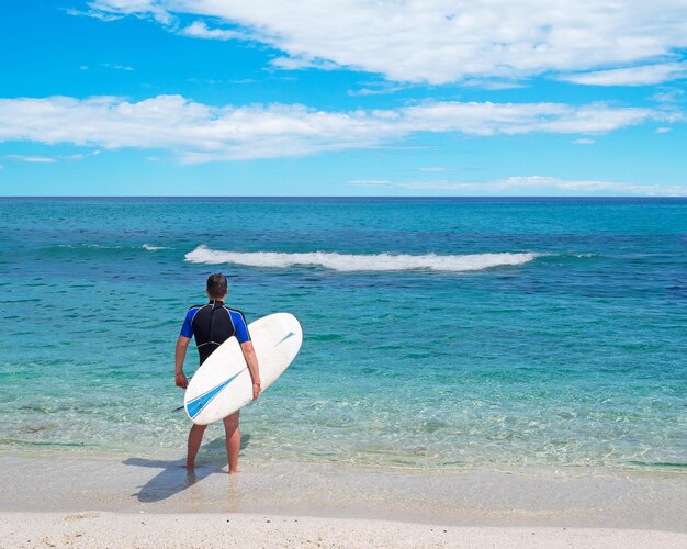 Surfista con tavola da surf in riva al mare