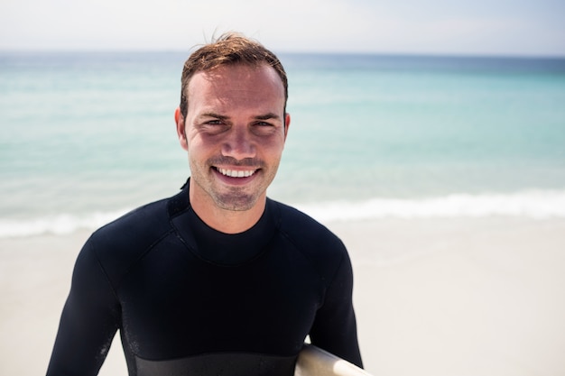 Surfista felice in piedi sulla spiaggia