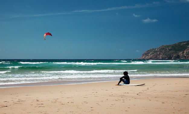 Surfista seduto sulla spiaggia