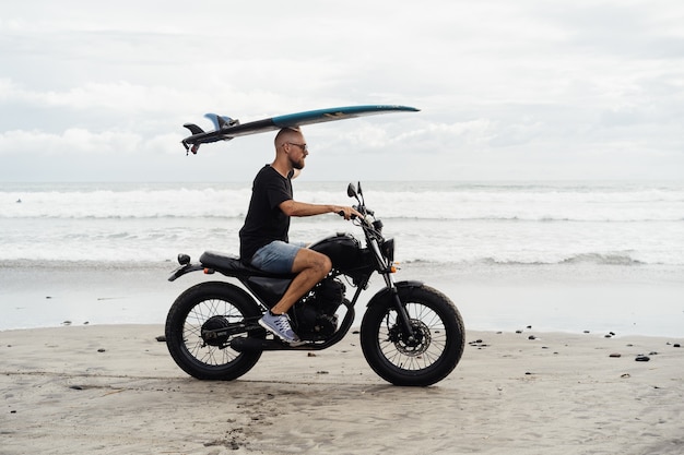 Surfista su una moto con una tavola da surf