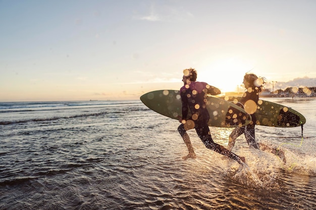 Surfisti che corrono nell'oceano con le tavole da surf