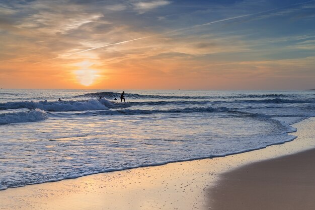 Surfisti che praticano surf al tramonto.