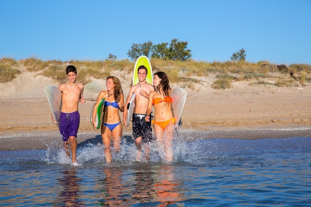 Surfisti della spiaggia del gruppo dei surfisti che spruzzano