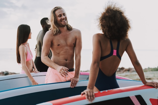 Surfisti maschii e femminili che parlano alla spiaggia.