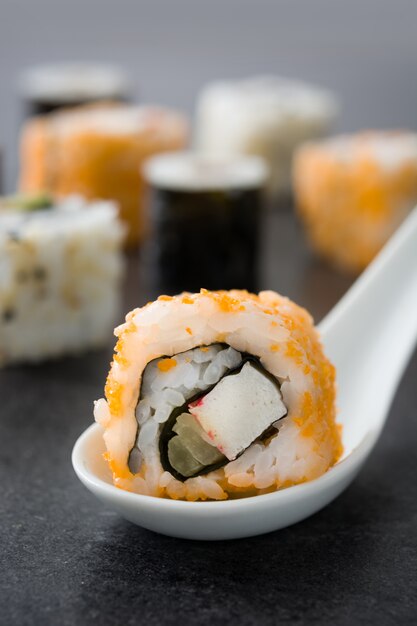 sushi arancio e arancio sul cucchiaio e sul nero