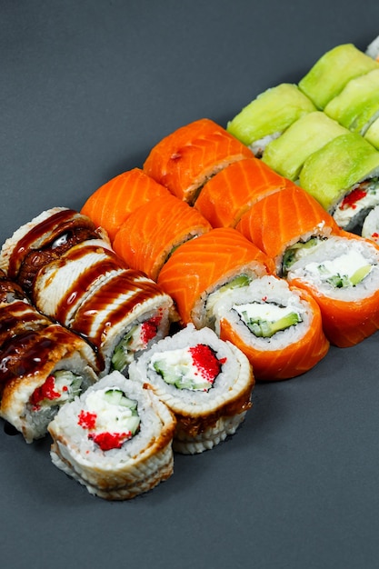 Sushi assortito. Rotolo di sushi con avocado, cetriolo. Rotolo di sushi con salmone e caviale. Rotolo di sushi con tonno e caviale. Su uno sfondo chiaro. Cibo giapponese. Vista dall'alto