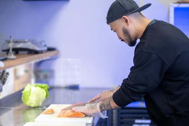 Sushi caffè. Sushi chef che taglia il pesce e prepara il sushi