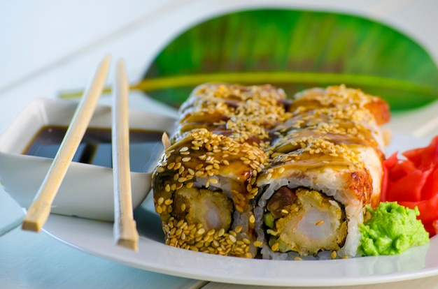 Sushi con tempuro di anguilla e gamberi su un piatto e uno sfondo bianco