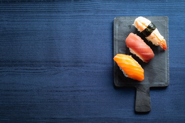 Sushi elegante su un tavolo di legno, un po' di Nigiri con salsa di soia e bastoncini.