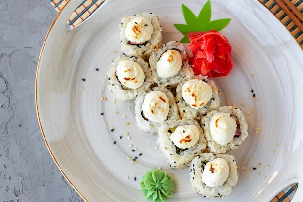 Sushi giapponese con semi di sesamo e glassa alla crema su sfondo grigio