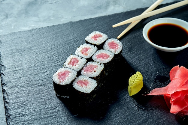 Sushi maki appetitosi con tonno su una tavola di ardesia nera