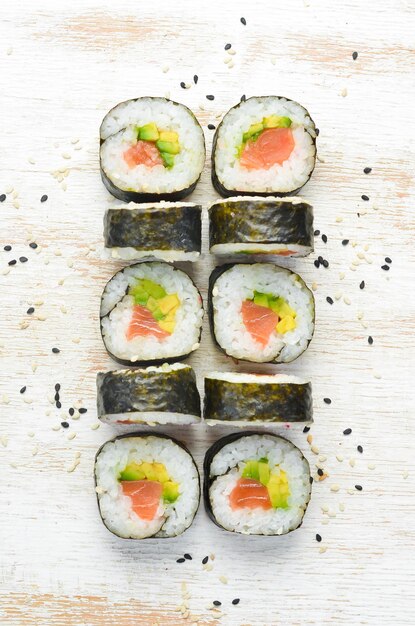 Sushi maki con salmone, avocado e nori Spazio libero per il testo Cucina tradizionale giapponese Vista dall'alto Stile rustico