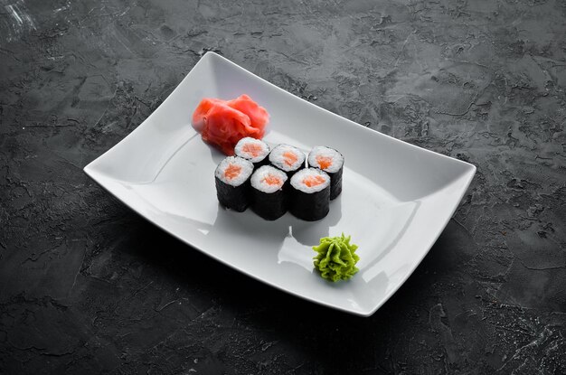 Sushi roll maki con salmone Cucina giapponese Vista dall'alto su sfondo di pietra nera