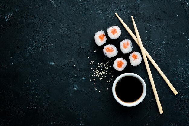 Sushi roll maki con salmone Cucina giapponese Vista dall'alto su sfondo di pietra nera