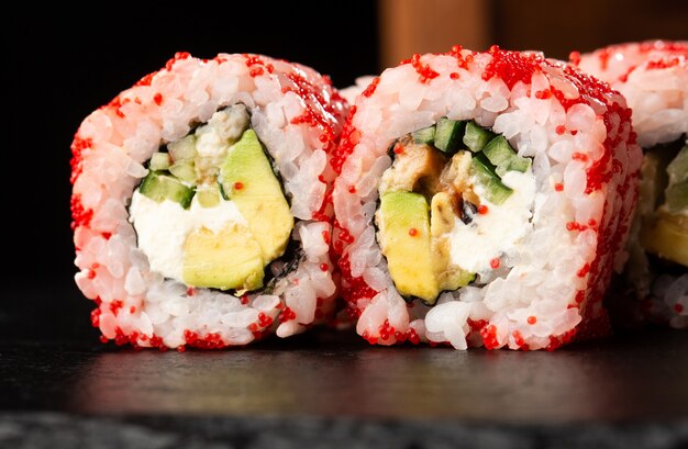 Sushi Rolls con avocado, anguilla, cetriolo e crema di formaggio all'interno sul nero