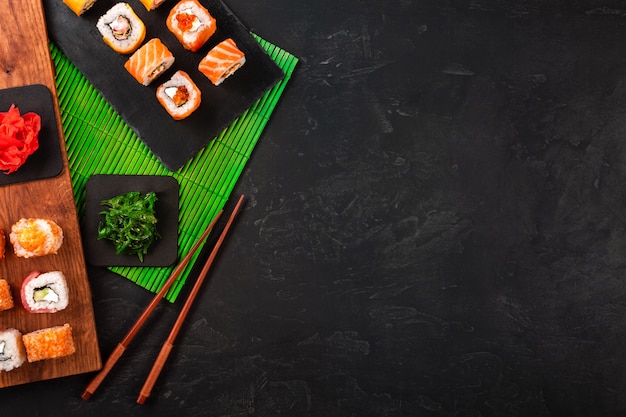 Sushi set con wasabi e zenzero sul vassoio di pietra nera sul tavolo nero.