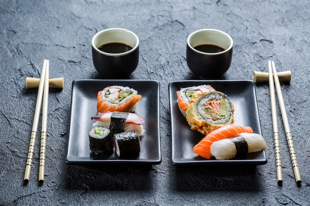 sushi su un piatto nero con le bacchette