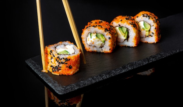 Sushi tradizionale e bacchette Cucina giapponese su sfondo nero