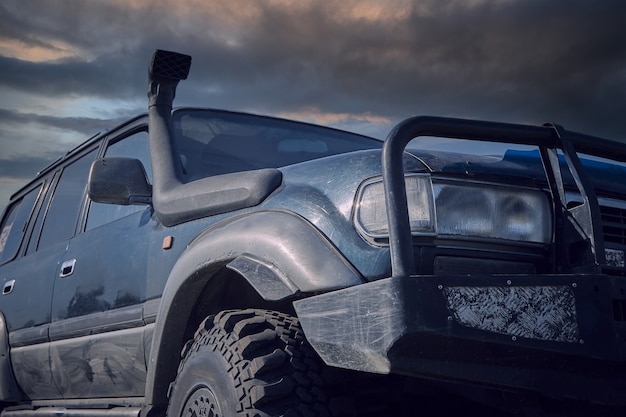 SUV 4x4 con boccaglio sullo sfondo di un cielo tempestoso. Il concetto di viaggio estremo.