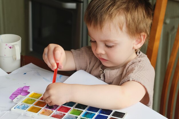 Svago domestico del bambino Ragazzino che dipinge con i colori