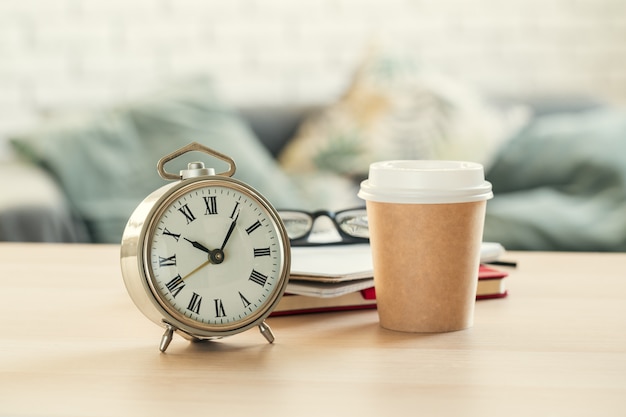 Sveglia d'annata classica e tazza di caffè su fondo di legno