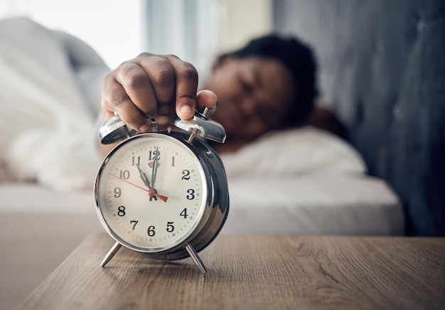 Sveglia sveglia o donna che dorme a letto la mattina dopo aver riposato premendo un pulsante snooze Mano assonnata sfocata o persona stanca a casa che si alza dal pisolino in camera da letto pronta per iniziare una nuova giornata