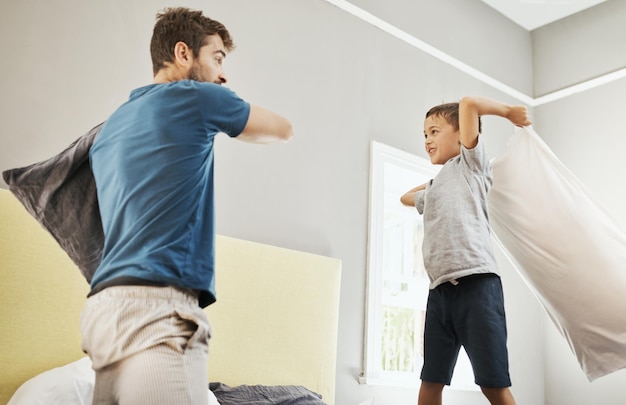 Svegliarsi con una lotta con i cuscini Inquadratura di un ragazzo e suo padre che trascorrono del tempo di qualità a casa