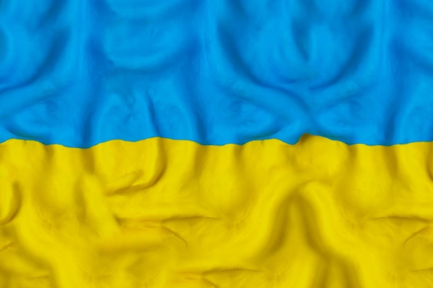 Sventolando la bandiera dell'Ucraina realizzata a mano con plastilina blu e gialla Pregate per l'Ucraina