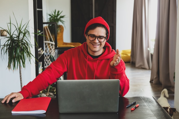 Sviluppatore giovane ragazzo in abiti rossi che lavora con il computer in ufficio a casa