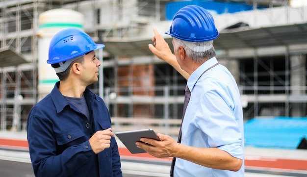 sviluppatori di architetti che esaminano i piani di costruzione in cantiere usando un tablet