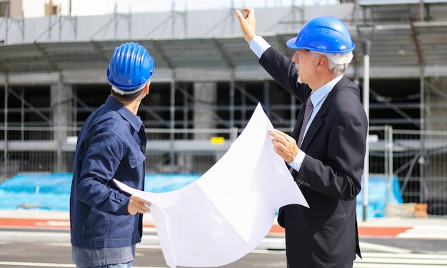 sviluppatori di architetti che esaminano i piani di costruzione in cantiere