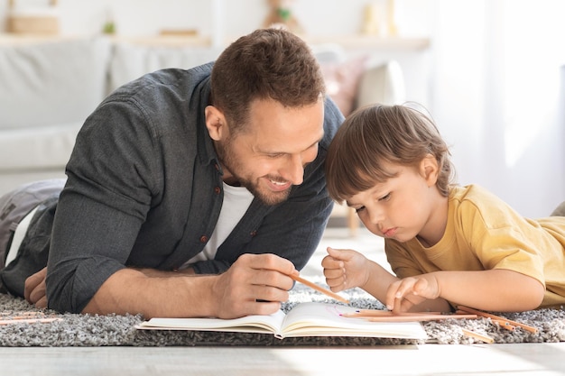 Sviluppo creativo dei bambini Ritratto ravvicinato di un padre positivo che disegna con il figlio piccolo con matite colorate