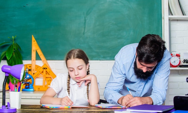 Sviluppo precoce dei bambini Studio della figlia con il padre Giornata degli insegnanti Giornata della conoscenza dello sviluppo del bambino Istruzione domestica Ritorno a scuola Insegnante uomo barbuto con una bambina in classe