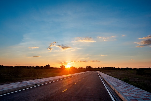 Svuoti il backgroung del cielo blu e del tramonto della strada asfaltata con lo spazio della copia