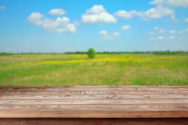 Svuoti la tavola di legno contro lo sfondo del campo sbocciante della molla. Uno spazio vuoto per il tuo oggetto.