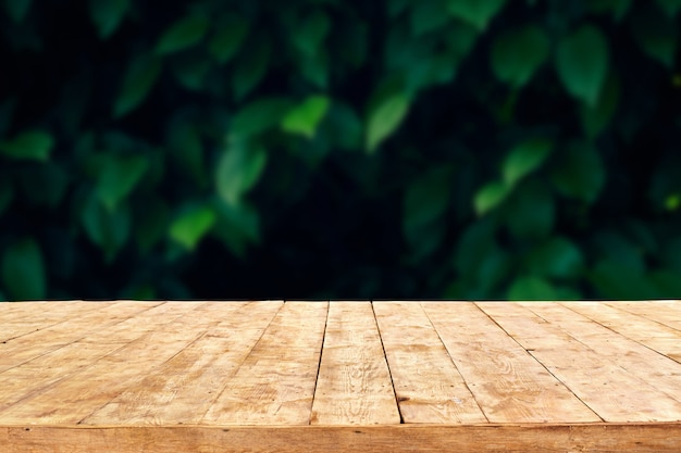 Svuoti la tavola di legno della piattaforma con il fondo del bokeh del fogliame. Pronto per il montaggio del display del prodotto.