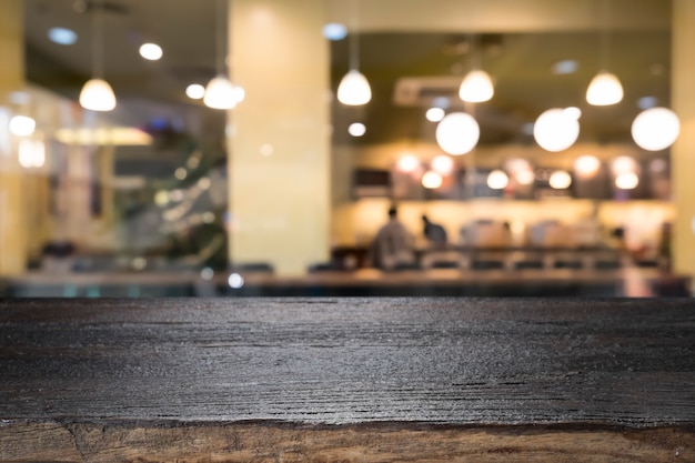 Svuoti la tavola di legno sul fondo della caffetteria della sfuocatura